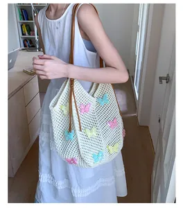 Détail du sac de plage tissé blanc avec papillons en perles colorées et anses en cuir