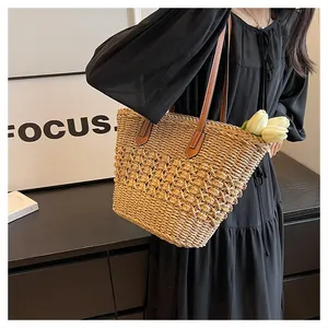 Detail of hand-woven straw tote featuring brown leather straps and rich braided texture