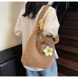 Detail of handwoven straw tote bag featuring a white frangipani flower decoration