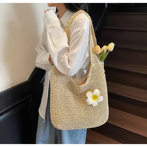 Detail of a large straw beach tote with white plumeria flower accents and shoulder straps