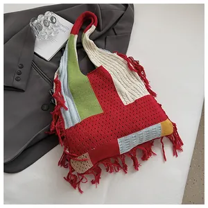 Detail of bohemian knit tote bag with colorful patchwork patterns and red fringe accents
