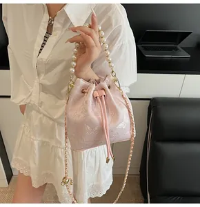Detail of pink embroidered bucket bag featuring floral patterns and a pearl handle