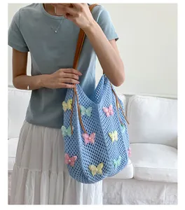 Détail du sac cabas au crochet bleu avec papillons 3D colorés et anses en cuir brun