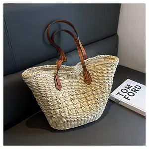 Detail of cream woven straw tote bag with premium brown leather handles and spacious interior