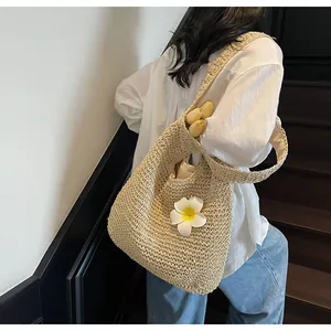Detail of hollow woven straw tote bag featuring white frangipani flower and beige lining