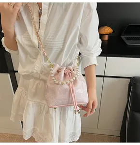 Detail of pink bucket bag with butterfly jacquard texture and pearl handle