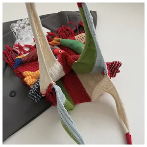 Macro view of colorful striped knit tote with tassels and a fish-shaped plush accessory