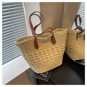 Detail of hollow woven texture on a beige straw tote bag with brown leather handles