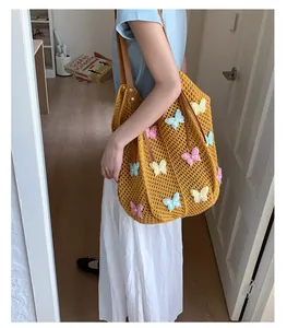 Détail du sac de plage tissé jaune gingembre avec broderies papillon 3D et anses en cuir marron
