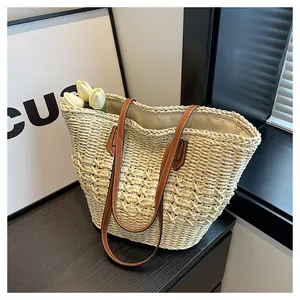 Detail of hand-woven straw tote with brown leather straps and fabric lining for summer