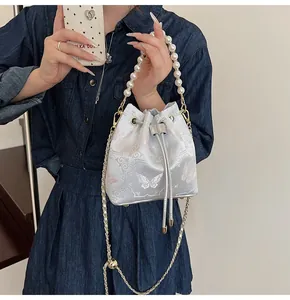 Detail of silver silk bucket bag with pink butterfly embroidery and pearl handle