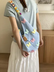 Blaue Stricktasche mit bunten Schmetterlings-Applikationen und floralem Häkelriemen
