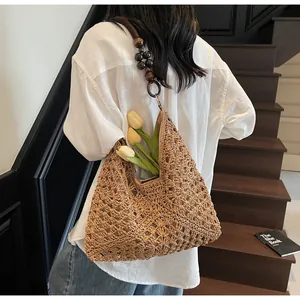Vue détaillée du sac en paille tressée évidée avec bandoulière en perles de bois