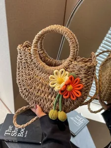 Handwoven semicircular straw bag with floral charms and dual-use handles for beach holidays