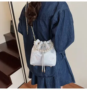 Detail of satin bucket bag featuring pearl handle, butterfly embroidery and drawstring