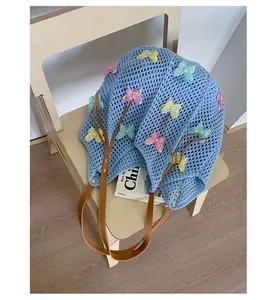 Détail d'un sac de plage tressé bleu clair avec papillons en maille 3D et perles nacrées