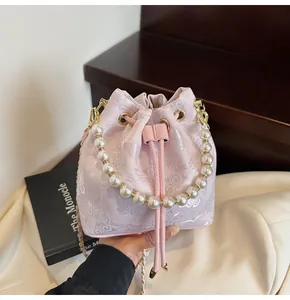Detail of pink embroidered bucket bag with pearl handle and floral butterfly patterns