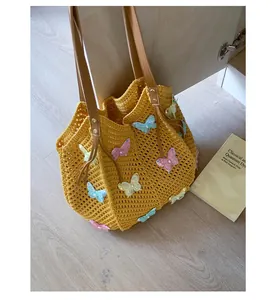 Détail du sac de plage en tricot jaune avec appliques papillon 3D colorées et anses en cuir