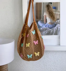 Détail du sac de plage tissé avec écussons papillon colorés et ornements de perles