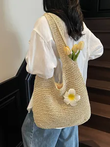 Straw tote bag with floral detail worn by model on shoulder for beach vacation style