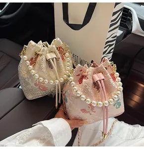 Close-up of embroidered drawstring bucket bags with pearl handles and floral jacquard