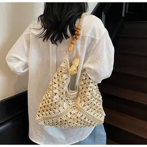 Détail du sac bandoulière en paille ajourée avec bandoulière en perles de bois et tulipe
