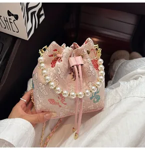Close-up of pink brocade bucket bag with butterfly embroidery and pearl handle