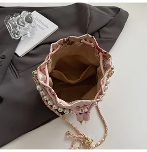 Detail of pink embroidered bucket bag featuring large pearls and interior zip pocket