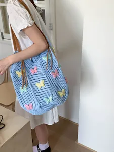 Sac de plage en tricot bleu avec écussons papillons colorés et anses en cuir marron