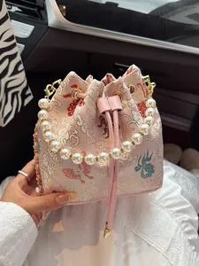 Pink embroidered drawstring bucket bag with pearl handle and golden butterfly patterns