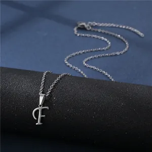 Close-up of a polished stainless steel letter F pendant on a delicate chain necklace