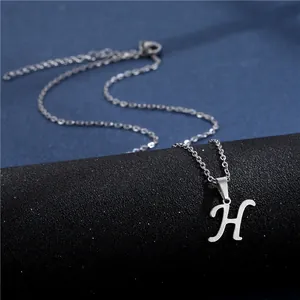 Macro shot of silver cursive letter H pendant on a polished stainless steel chain