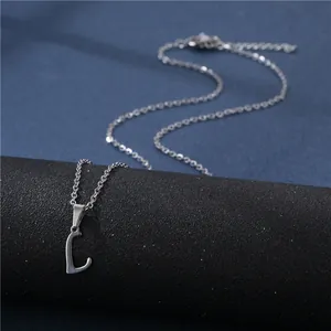 Macro view of polished silver capital letter L pendant on a delicate chain necklace