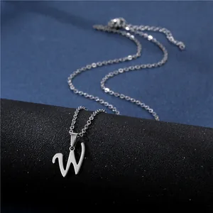 Macro detail of silver cursive letter W pendant on minimalist stainless steel chain