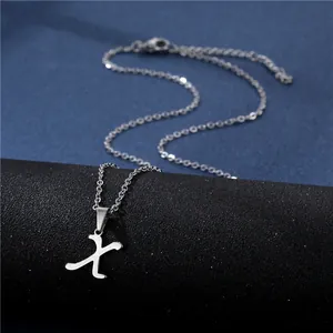 Macro shot of silver stainless steel letter X pendant with elegant fine chain necklace
