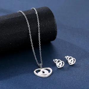 Polished stainless steel heart-shaped necklace and stud earrings set on blue background