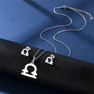 Detailed view of silver Libra zodiac necklace and stud earrings set on a display stand