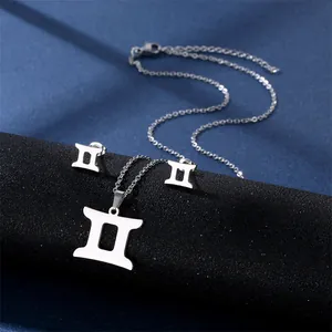 Polished silver Gemini zodiac necklace and stud earrings set on a dark blue silk fabric