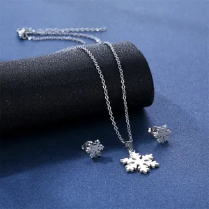 Minimalist stainless steel snowflake pendant necklace and earrings set on blue background
