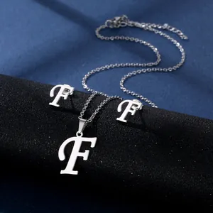 Detailsicht der silbernen Edelstahlkette und Ohrstecker mit geschwungenem Buchstaben F