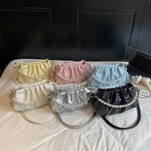 Collection of pleated cloud bags in six colors with pearl straps on a white bedding