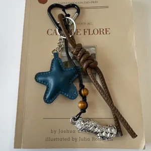 Detail of vintage bag charm with blue leather star, silver peanut pendant and heart carabiner
