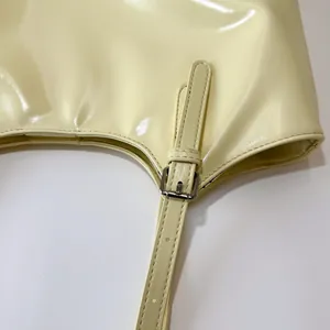 Detail view of yellow patent leather shoulder bag showing adjustable strap and metal buckle