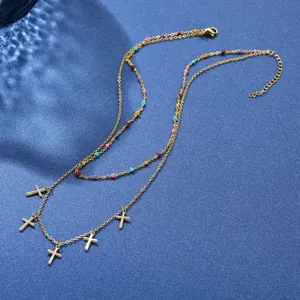 Collier doré double épaisseur avec perles colorées et cinq petits pendentifs croix sur bleu
