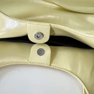 Detail of magnetic silver closures and smooth pale yellow leather on this tote bag