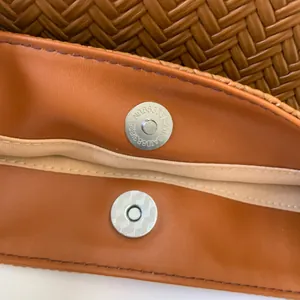 Detailed macro view of the metal magnetic closure on a brown woven texture bucket bag