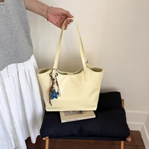 Detail of cream leather tote bag featuring a decorative star charm and bead pendant