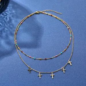 Collier doré double épaisseur avec perles colorées et cinq pendentifs croix sur velours