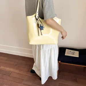 Close-up of cream tote bag with star charm and braided pendant on model shoulder