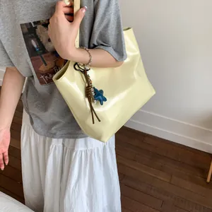 Close-up of shiny cream tote bag featuring a star pendant and woven rope detail